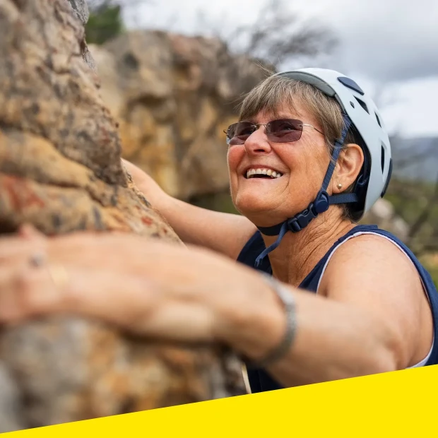 An image of a woman rock climbing while smiling.