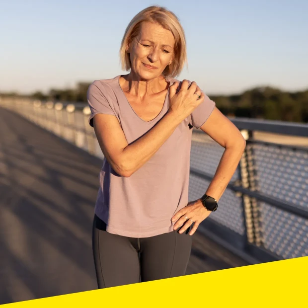 A woman touching her shoulder in discomfort or pain.