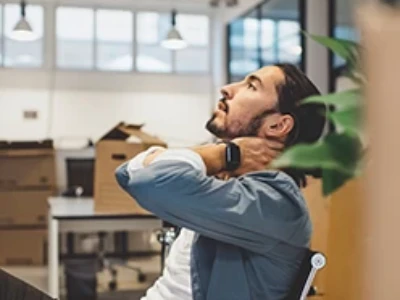 A man pensively looking upwards while leaning back in a chair.