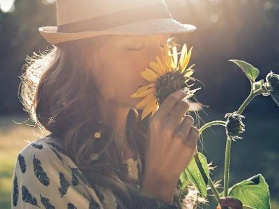 Seorang wanita sedang mencium bunga matahari