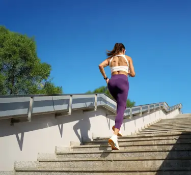 Active woman dressed in sportswear climbing stairs outdoors