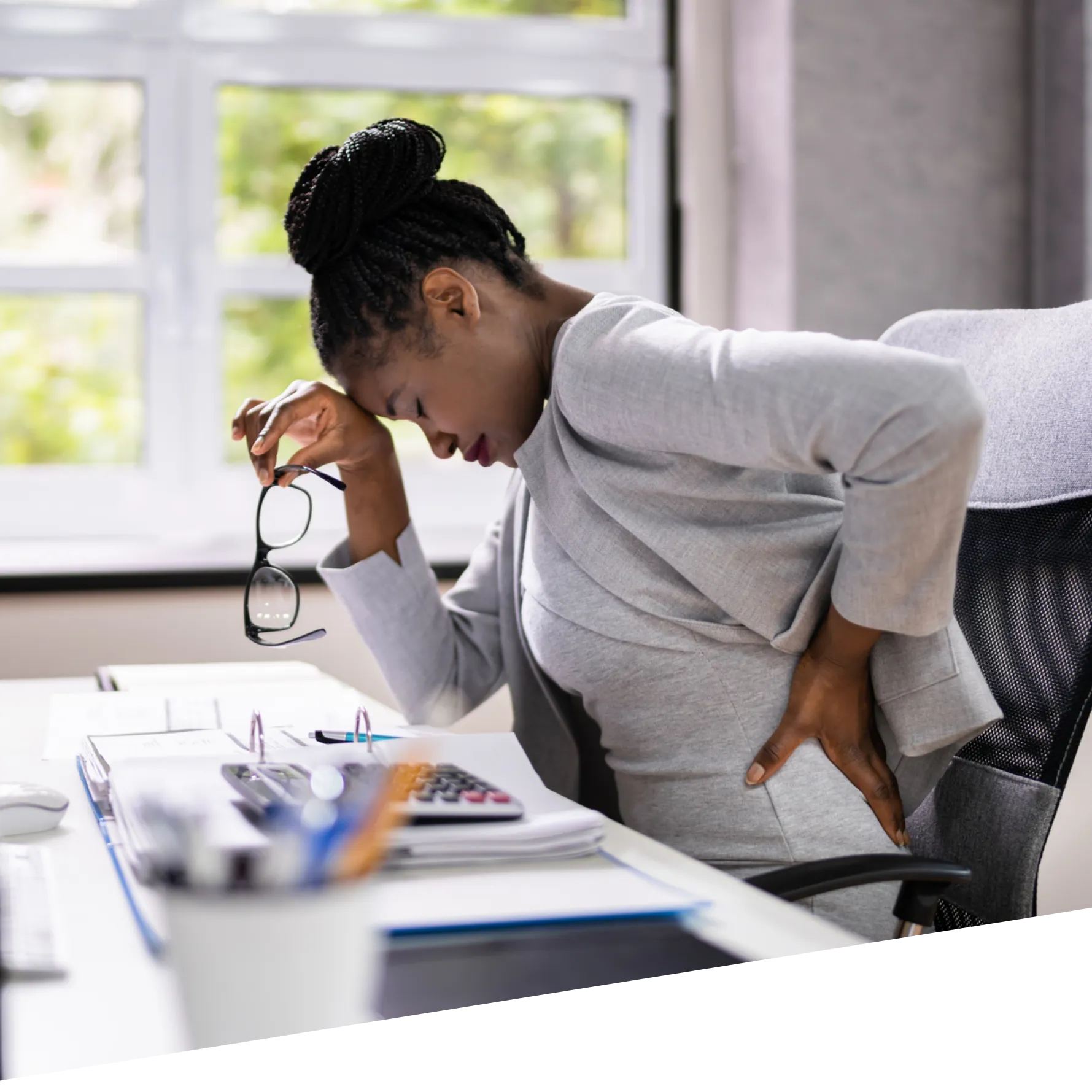 A woman holds her lower back due to discomfort or pain.