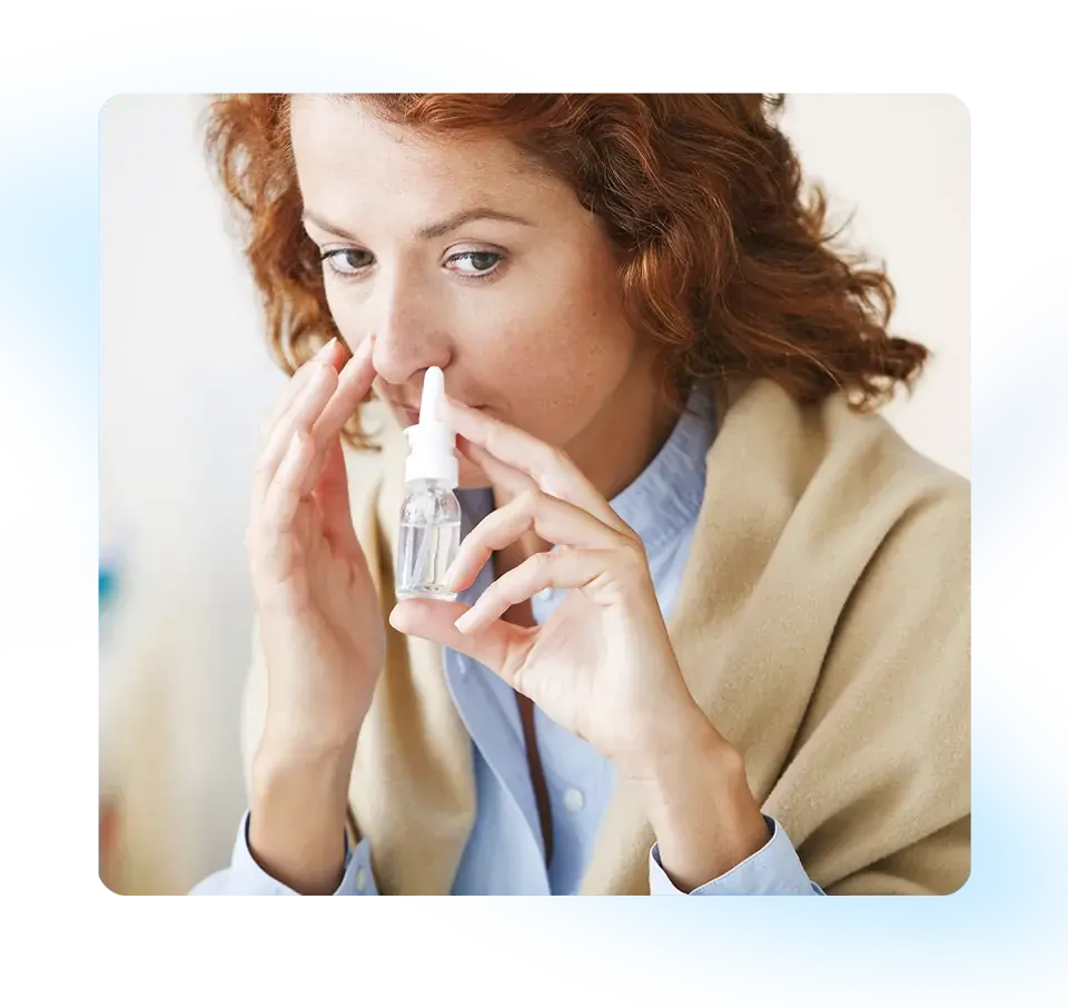 a woman  uses a nasal spray