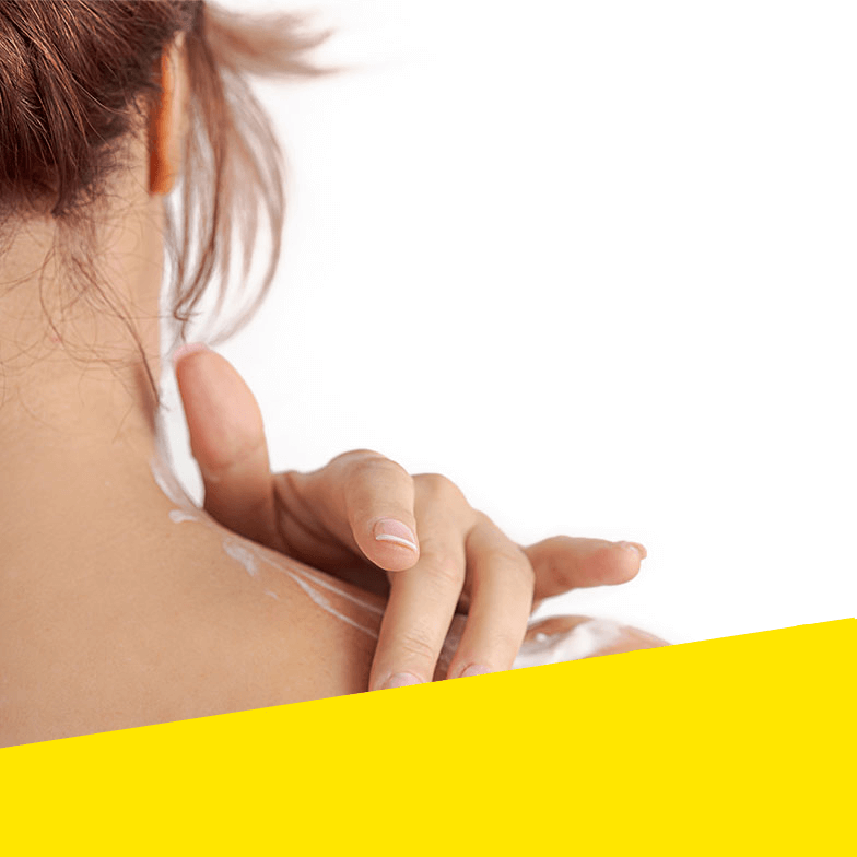 A woman rubs cream into her shoulder.