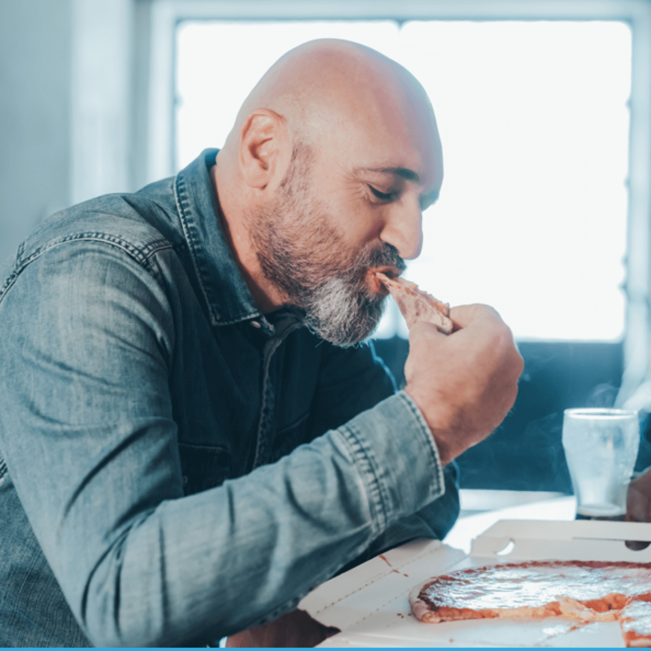 A bald man eating pizza happily.