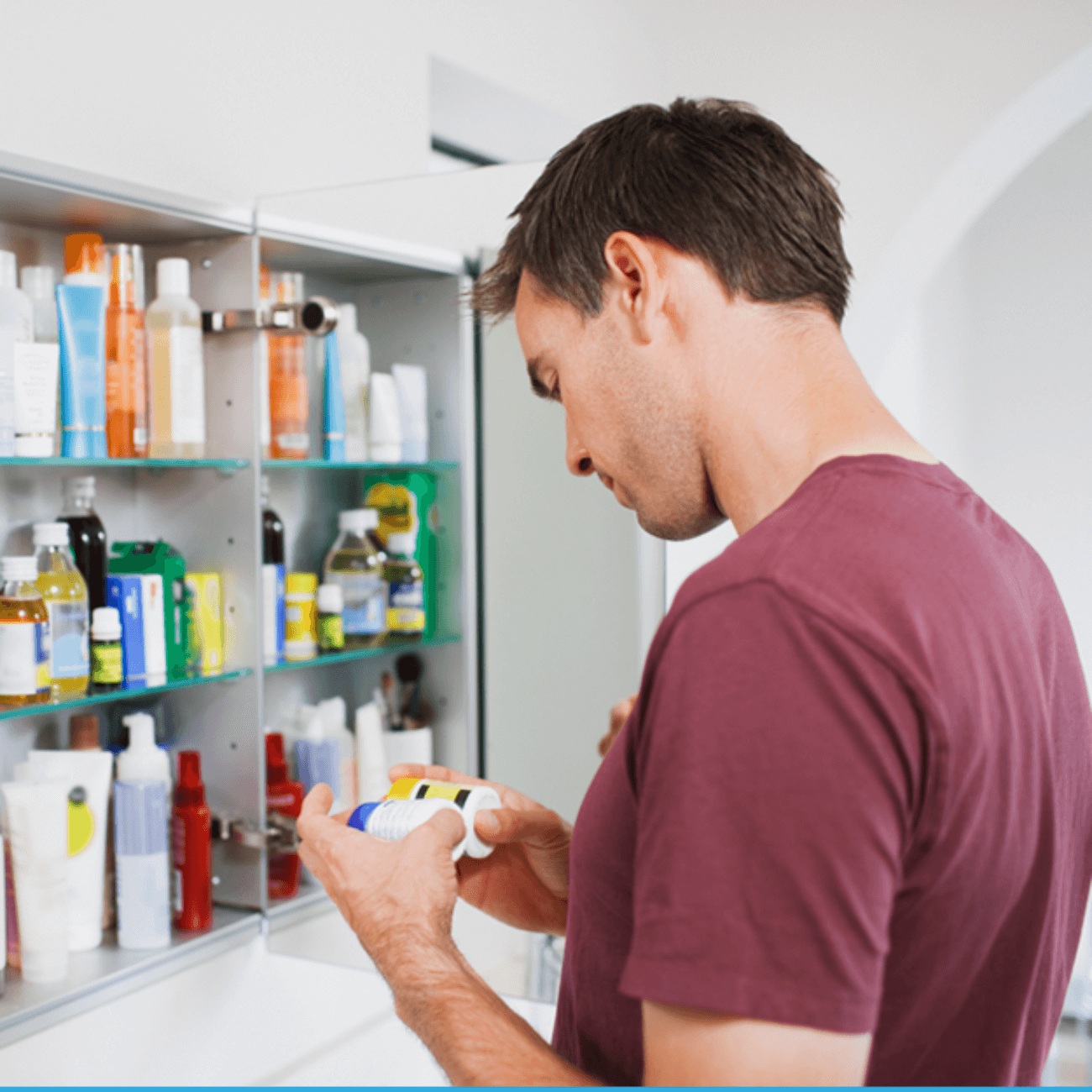 A man standing in his bathroom looking through his medicine cabinet.