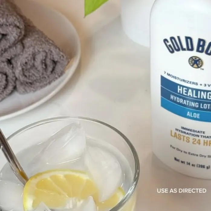 A hand squeezing a container of Gold Bond Eczema Relief cream, with the white cream visible on the other hand.