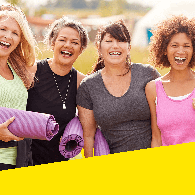 A group of women smile after doing yoga.
