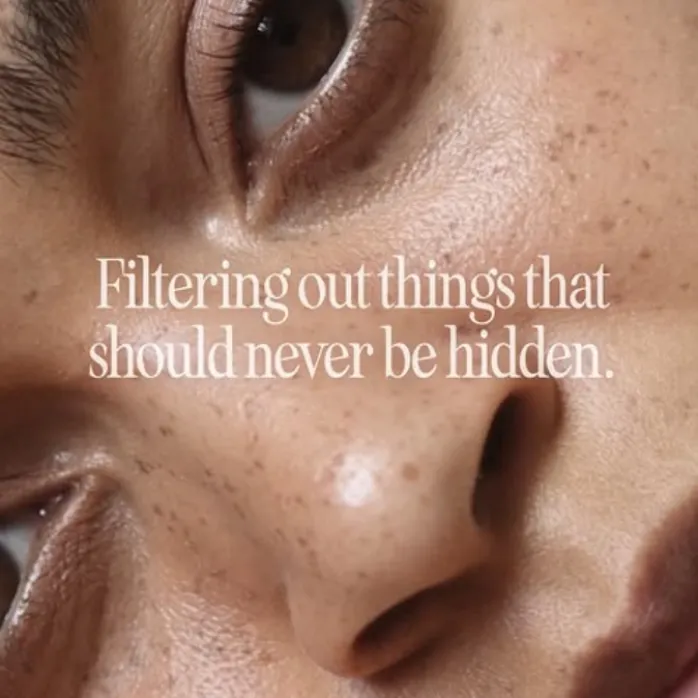 A woman with a warm smile, posing for the camera on a beige background.