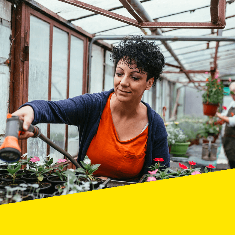 A woman waters her garden.